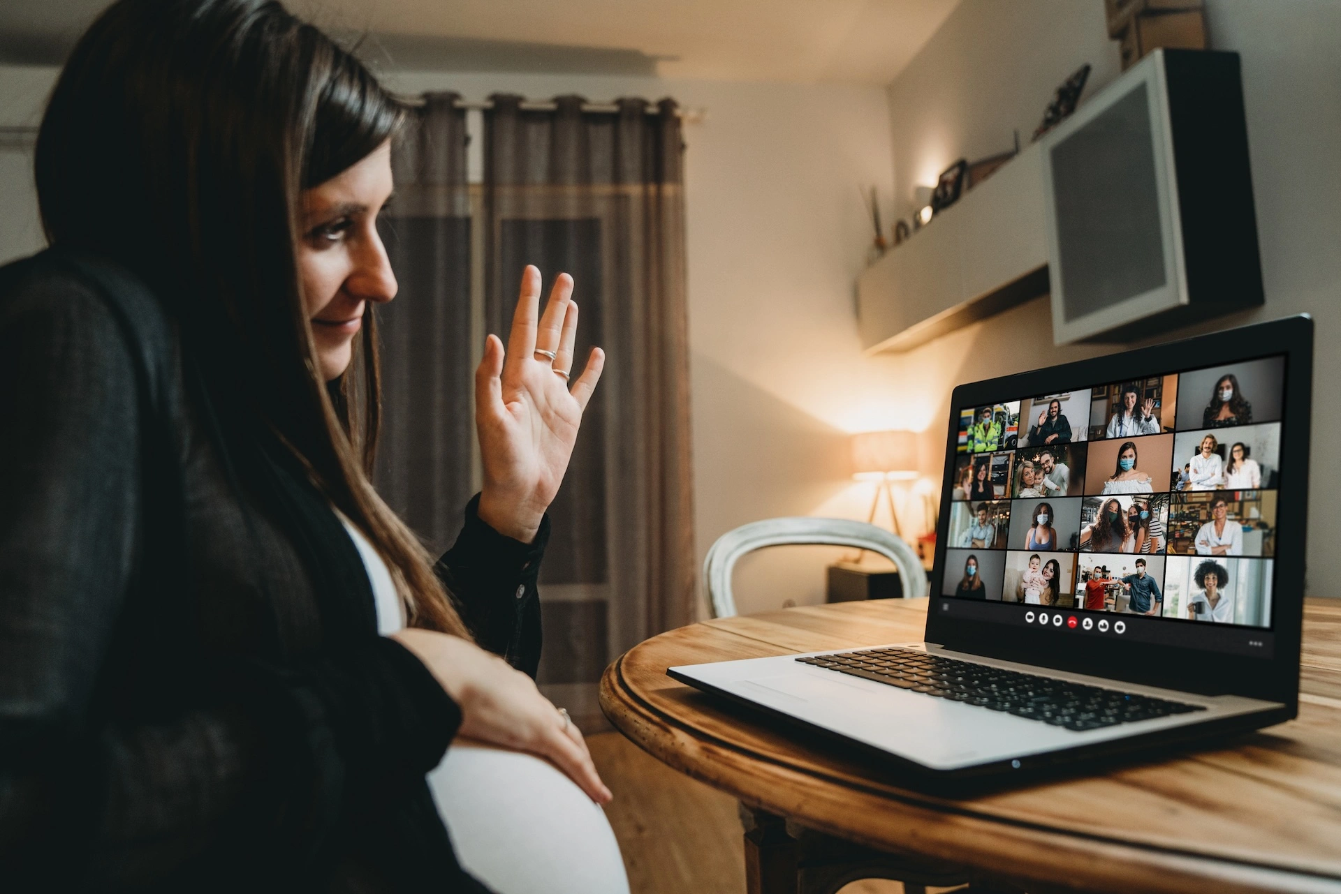 pregnant woman waves to webinar participants on computer screen
