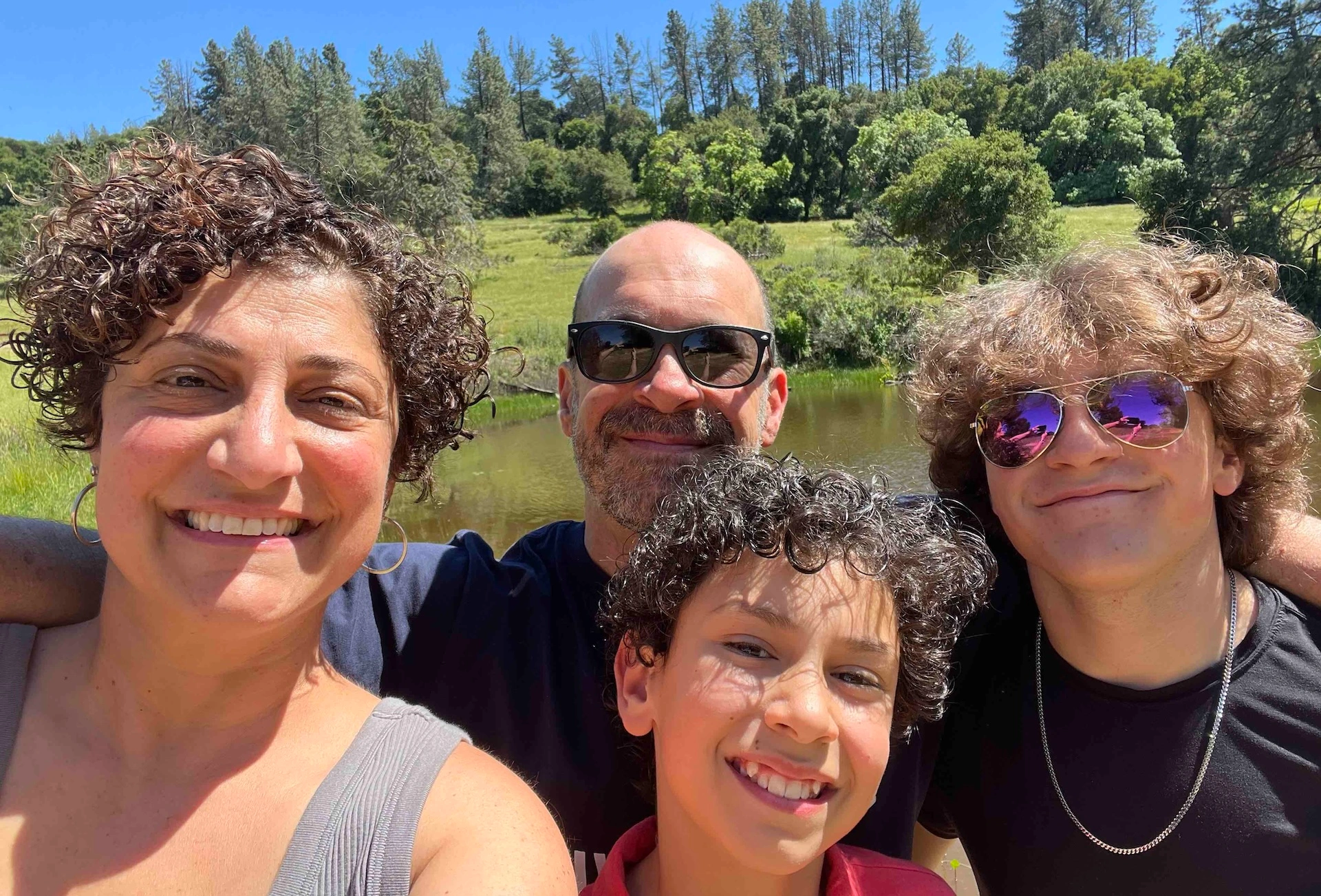 Isaac Ergas with his wife and two sons with trees in the background.